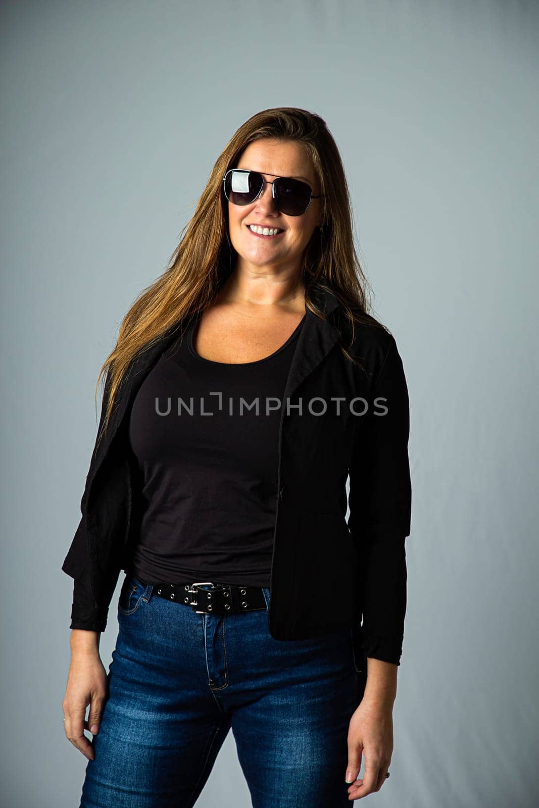 Forty year old woman, wearing sport coat and cop style sunglasses, isolated on a white background