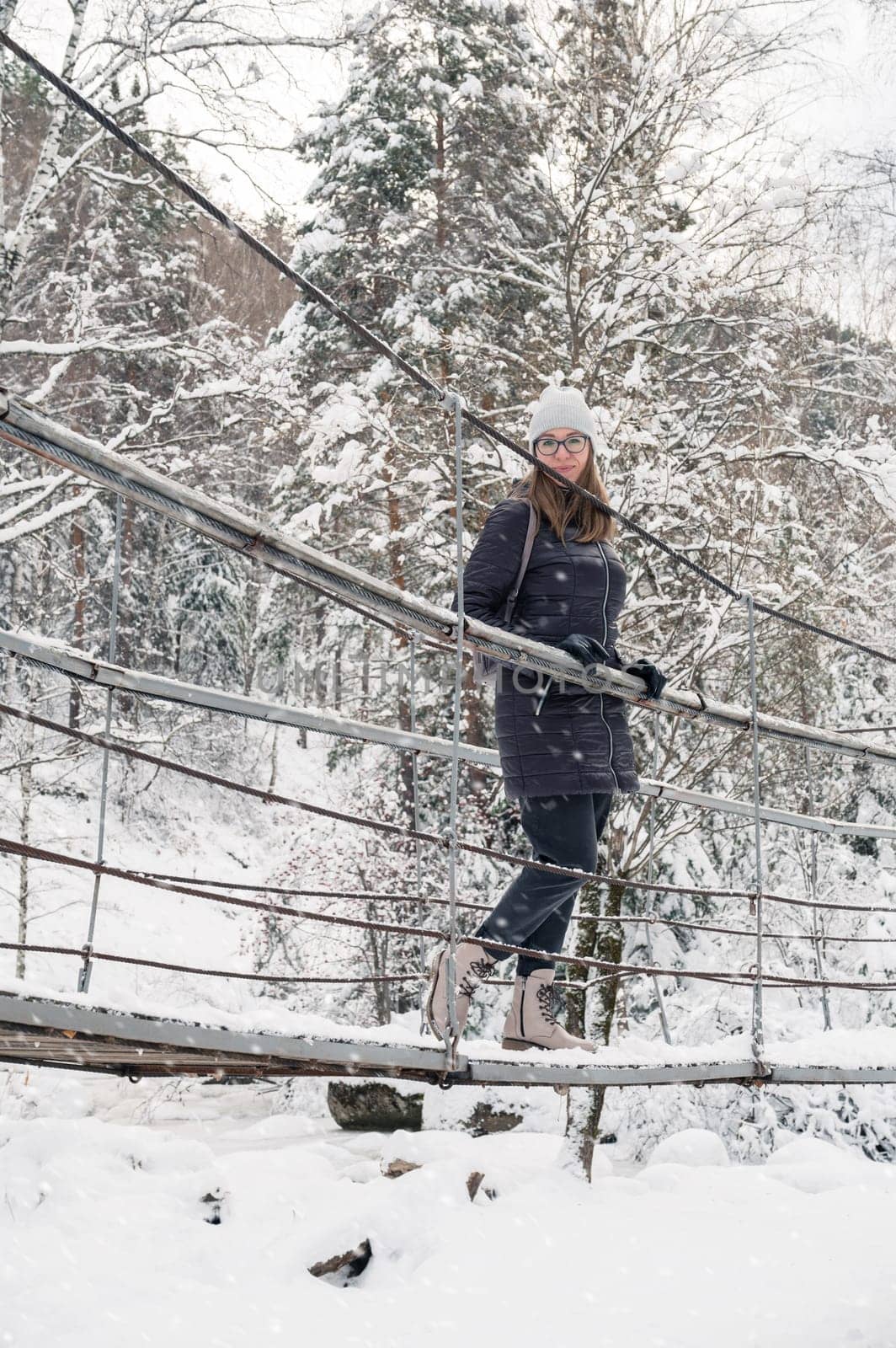 Woman in winter jacket walking in snowy winter forest, snowy winter day