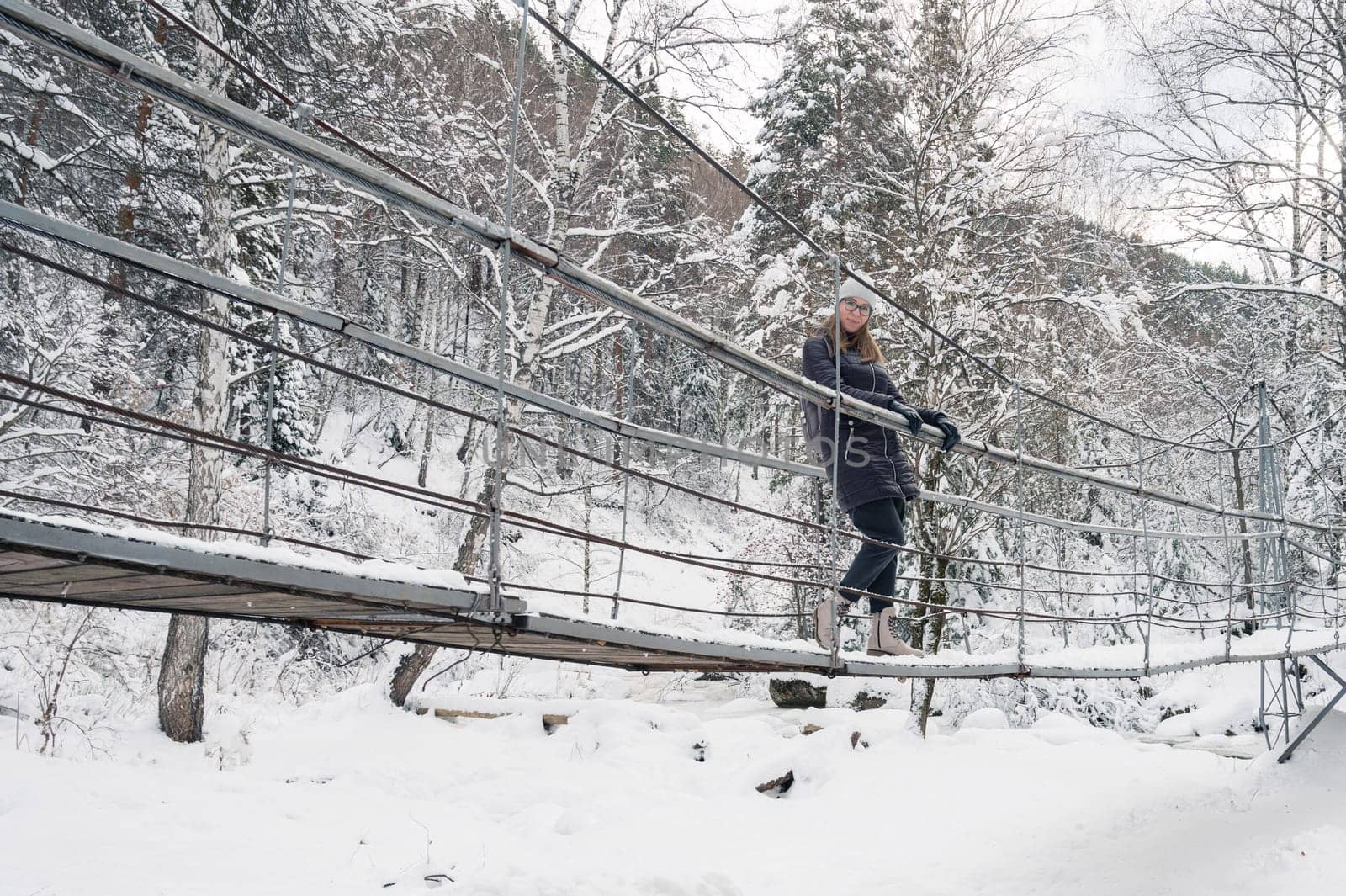 Woman in winter jacket walking in snowy winter forest, snowy winter day