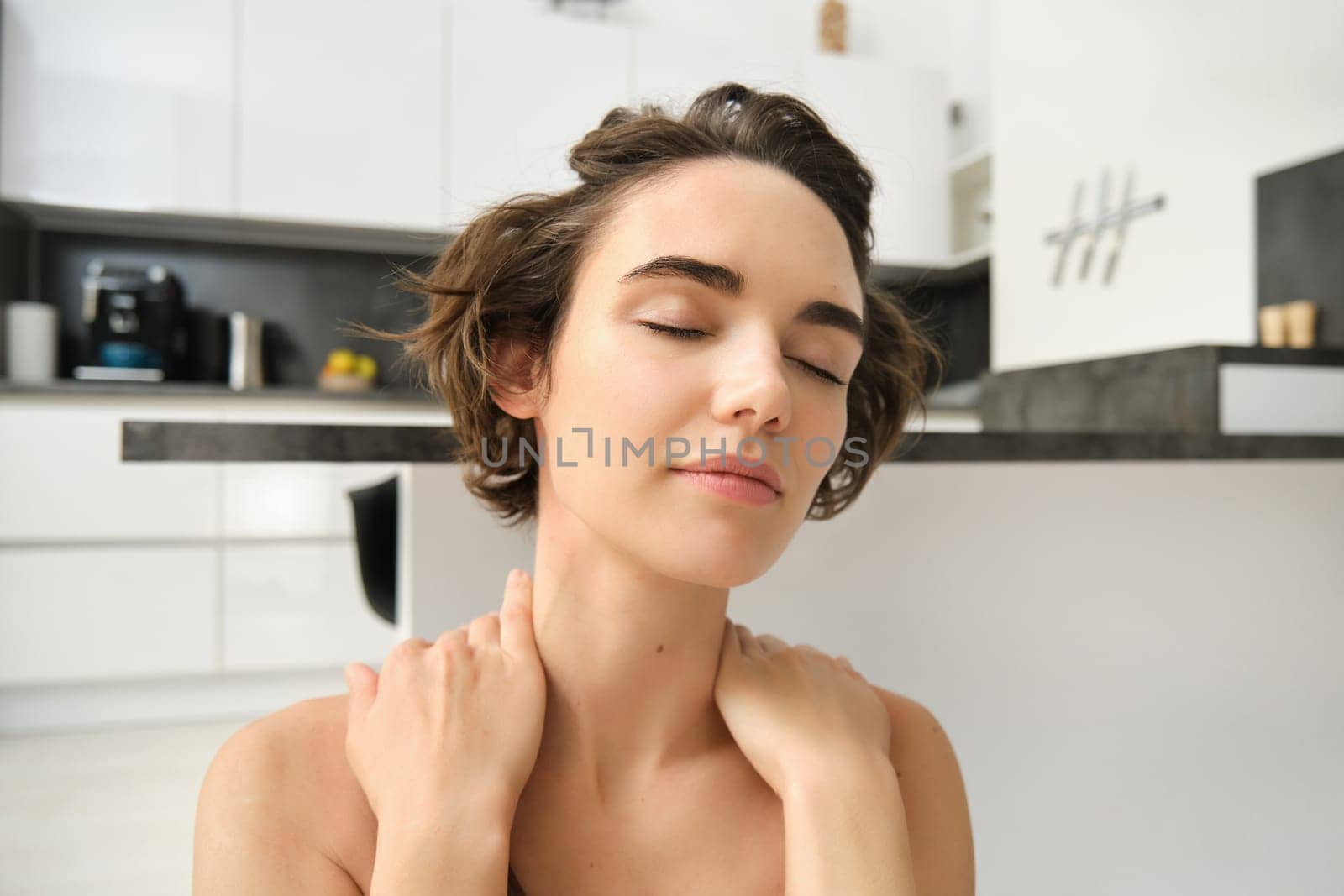 Home sports and wellbeing. Young brunette woman in sportswear, staying at home and doing yoga, mindful exercises, sitting in yoga pose with eyes closed and relaxed face. Copy space