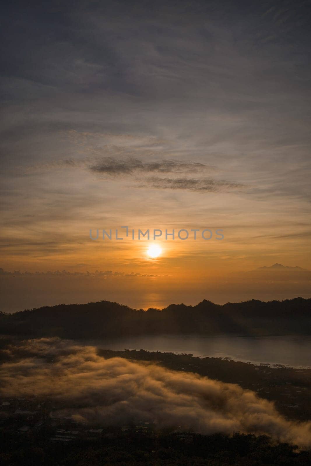 Amazing sunrise lake view at mount Batur. Dawns landscape photo at foggy Batur mount with orange sky