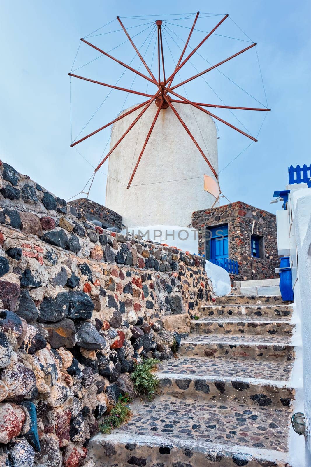 Old traditional whitewashed greek windmill on Santorini island in Oia town with stairs in street. Oia village, Santorini, Greece