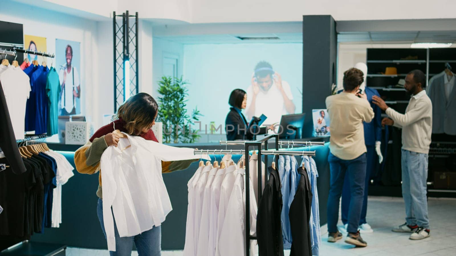 Female customer looking at merchandise in clothing store by DCStudio