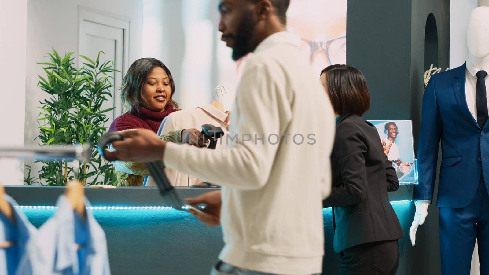 Asian client preparing to pay for clothes at cash register by DCStudio