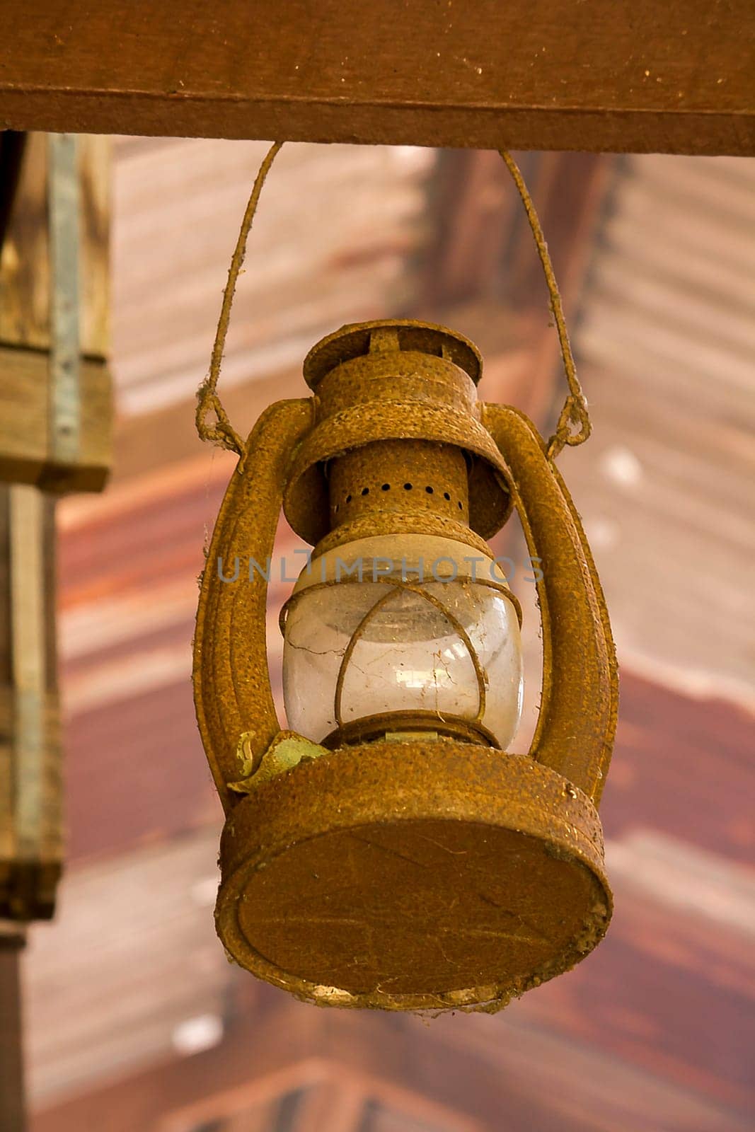 Old lantern hanging on a wooden beam.