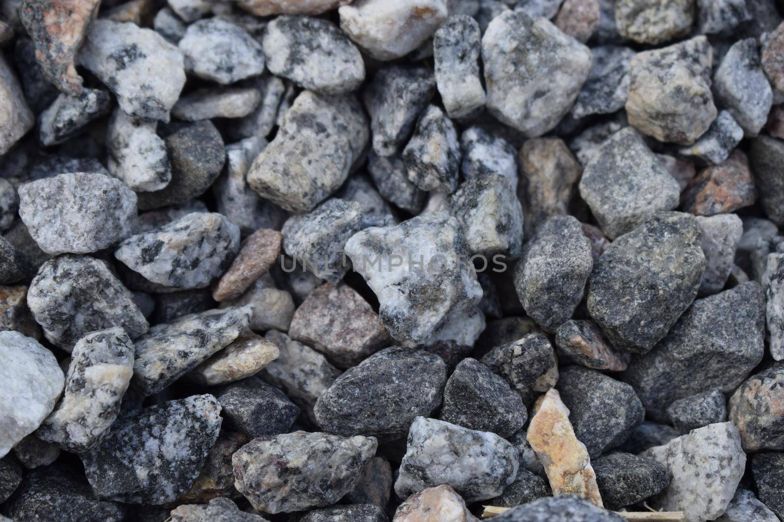 Gravel Rock Texture. Crushed stone and gravel on the ground. Texture background brown stones on a black earth background. Image of broken stones and gravel