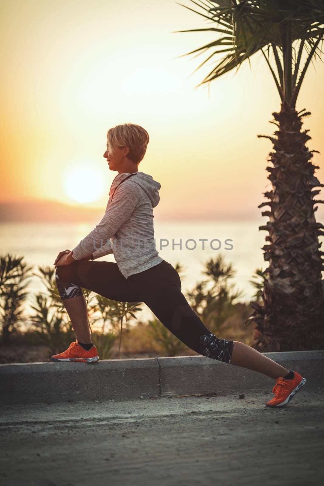 A beautiful young woman is doing stretching exercise by the sea in sunrise.