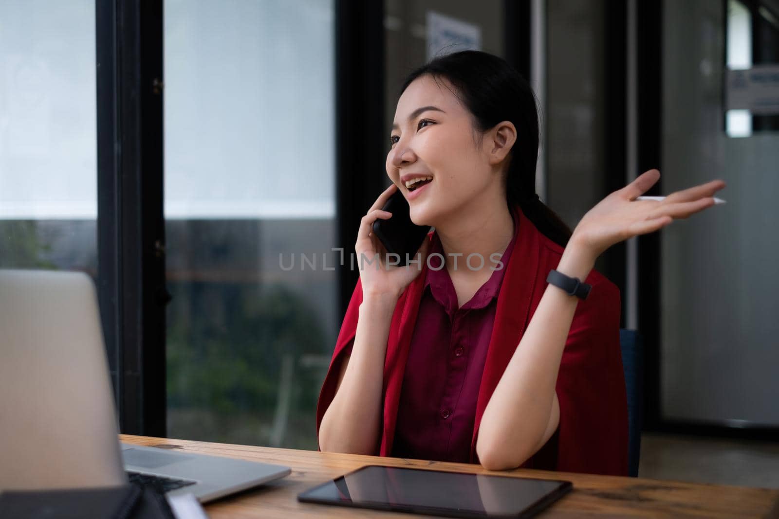 Photo of gorgeous secretary talking with customer by cell phone at office. she sitting at the wooden desk. by itchaznong