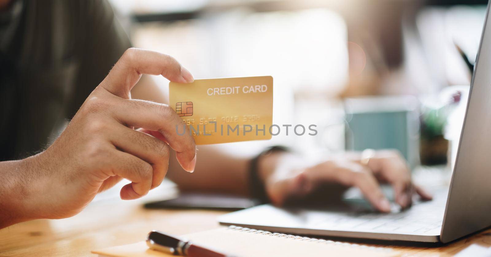 Online shopping concept, A man hands holding using mobile smart phone and credit card making online payment with laptop computer