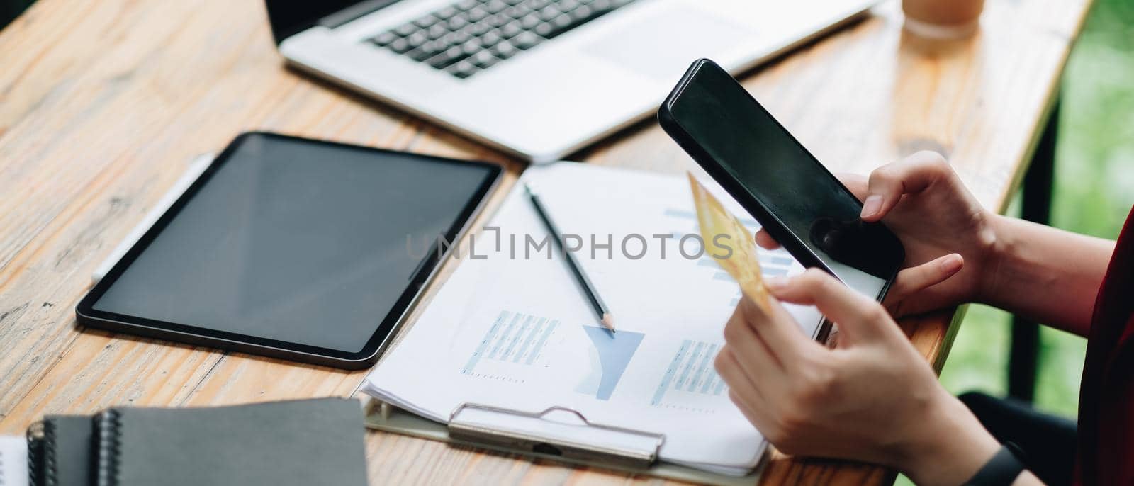 Woman using credit card and mobile phone for online shopping and internet payment via mobile banking application by nateemee