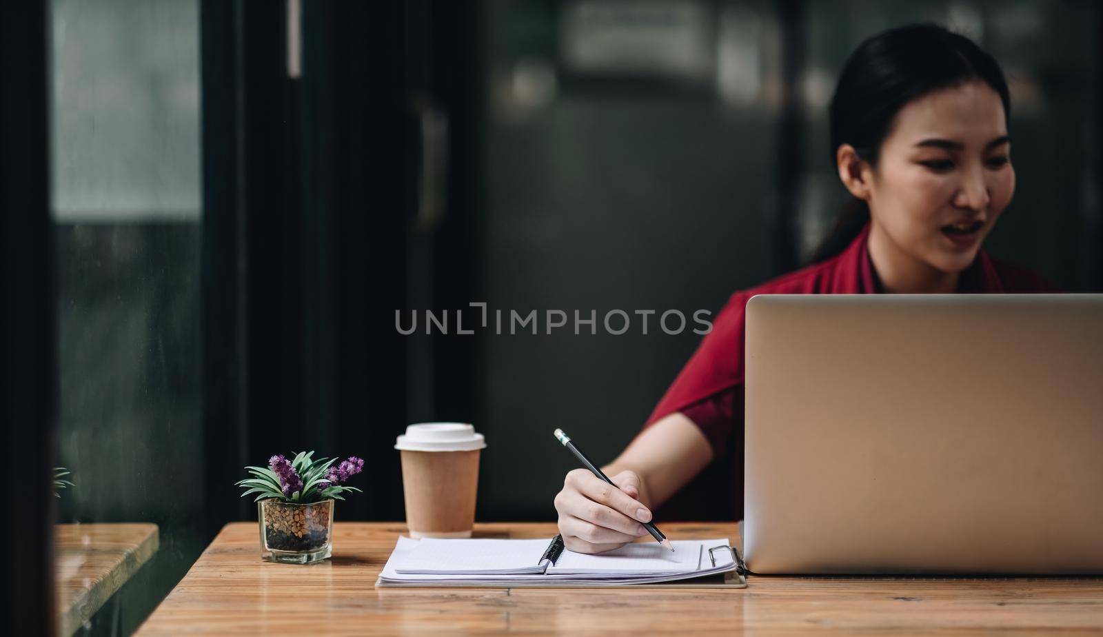 Cropped photo of woman writing making list taking notes in notepad working or learning on laptop indoors- educational course or training, seminar, education online concept by nateemee