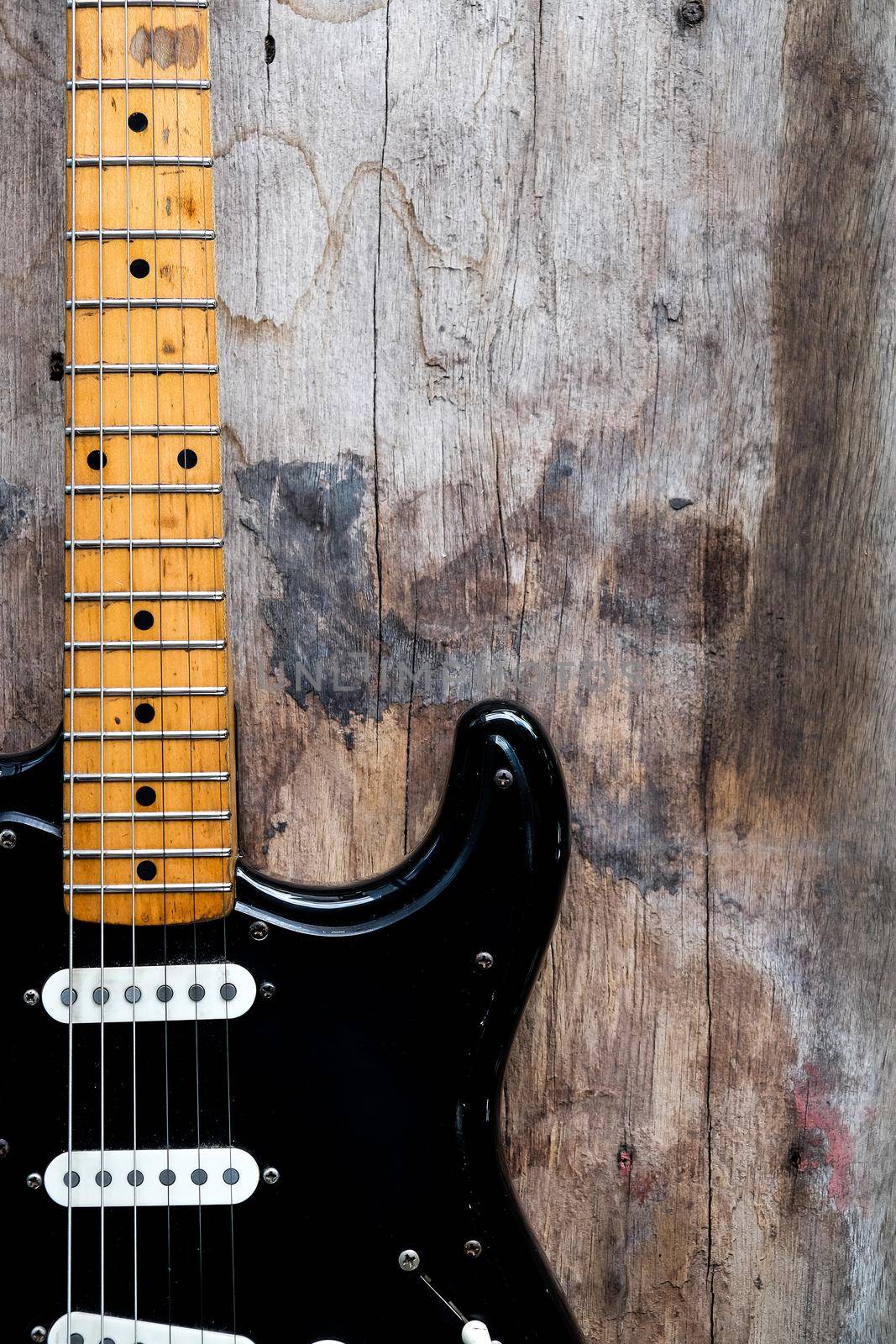 Detail of Black Electric Guitar on a wood background.