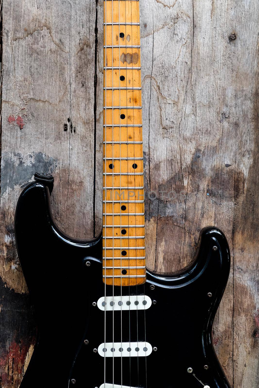 Detail of Black Electric Guitar on a wood background.