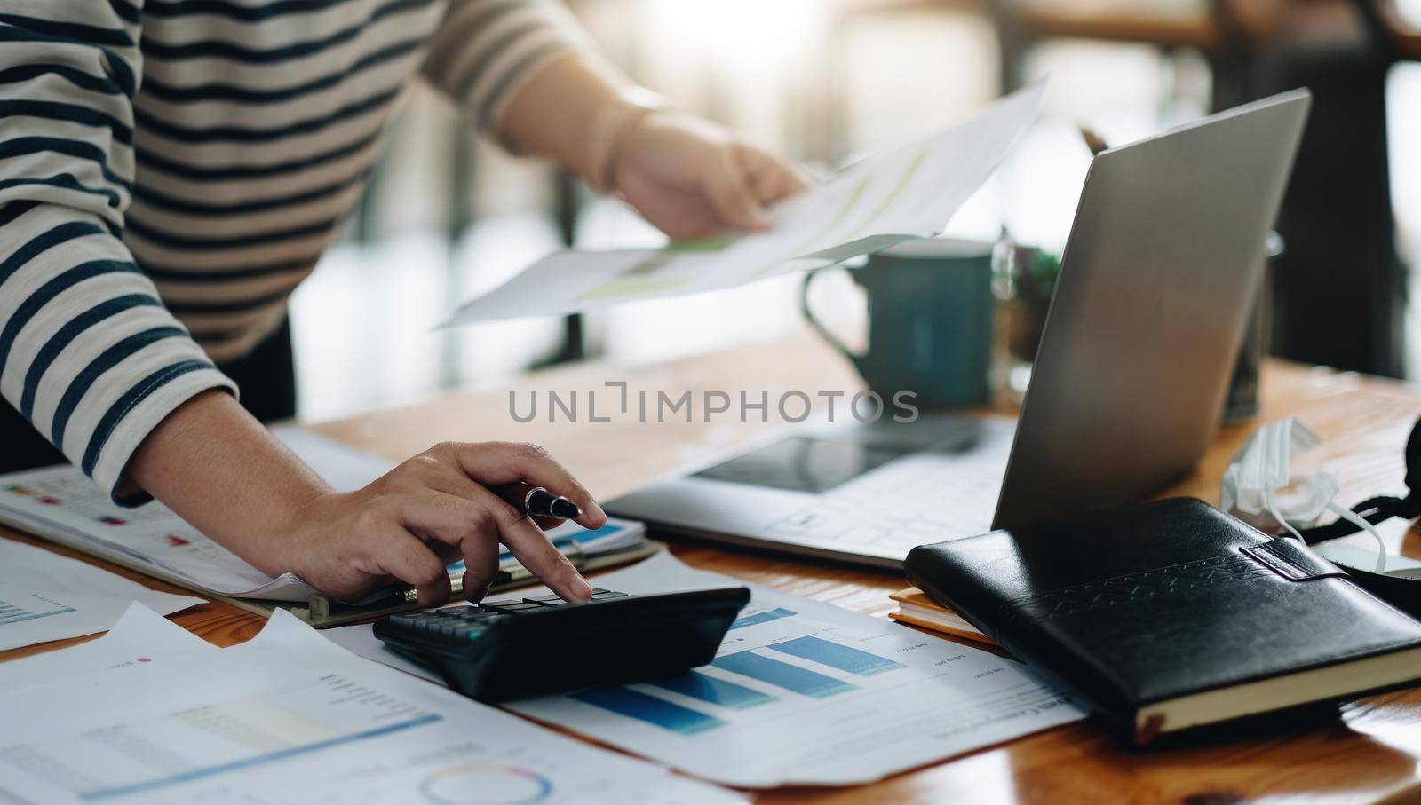 Close up accountant working on desk using calculator for calculate finance report at home office by nateemee