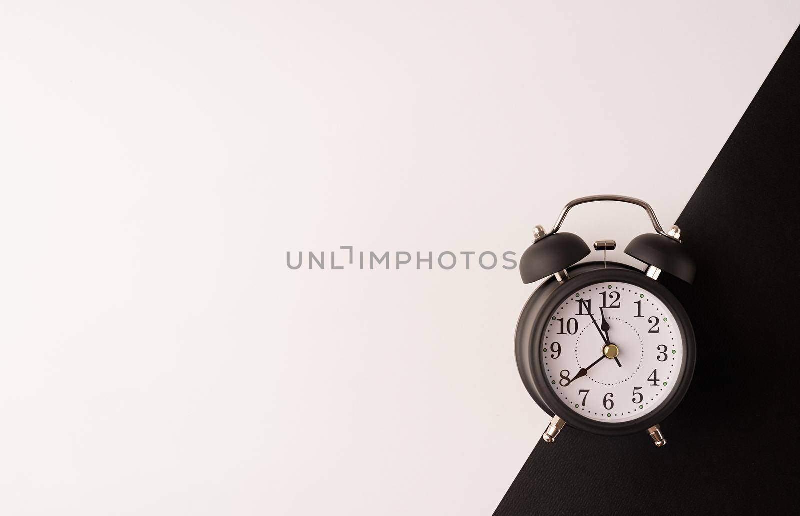 Time management, punctuality, business metaphors. White vintage alarm clock with nine ten on double white and black background, flat lay top view, copy space.