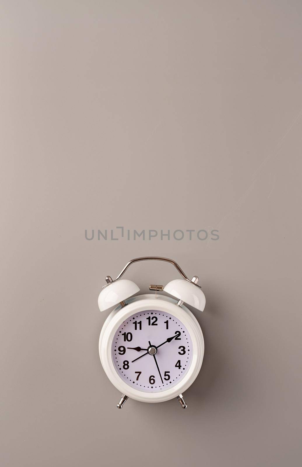 Time management, punctuality, business metaphors. White vintage alarm clock with nine ten on gray background, flat lay top view, copy space