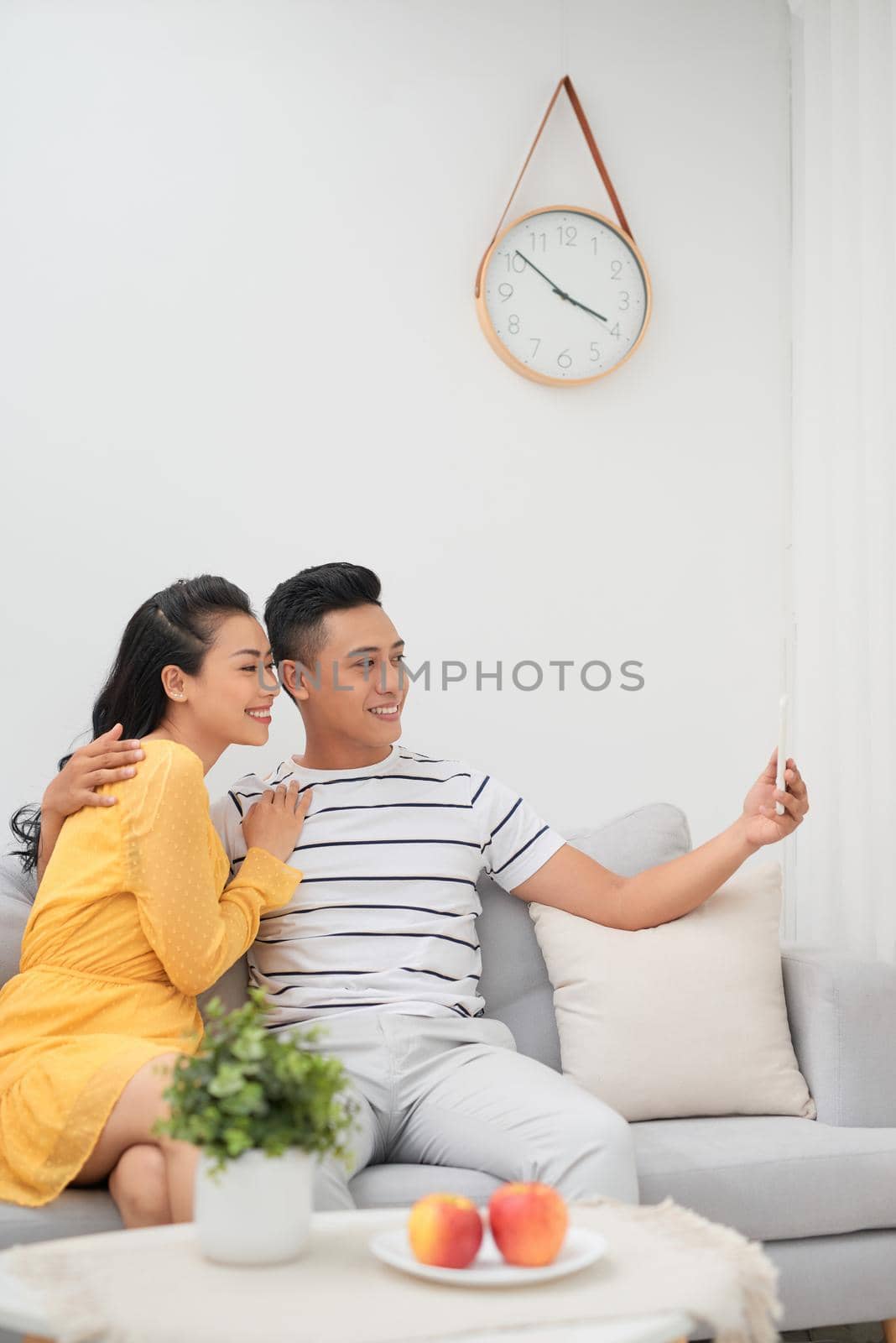 Asian couple using smartphone for selfie in living room at home