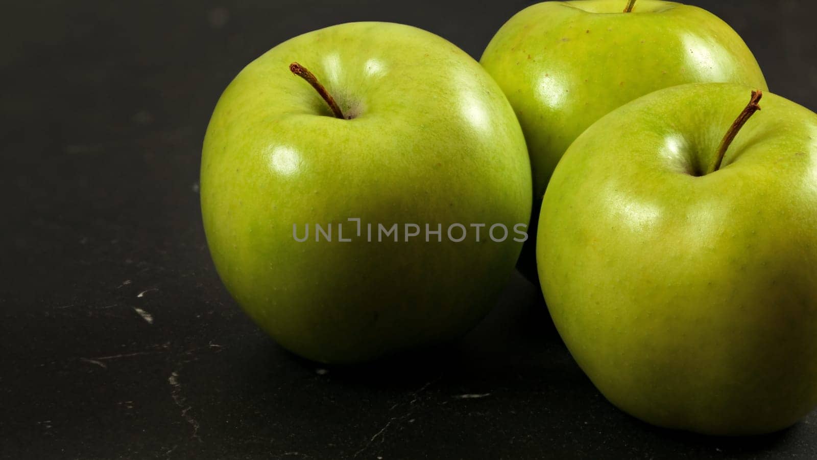 Closeup photo, green apples on black working board.