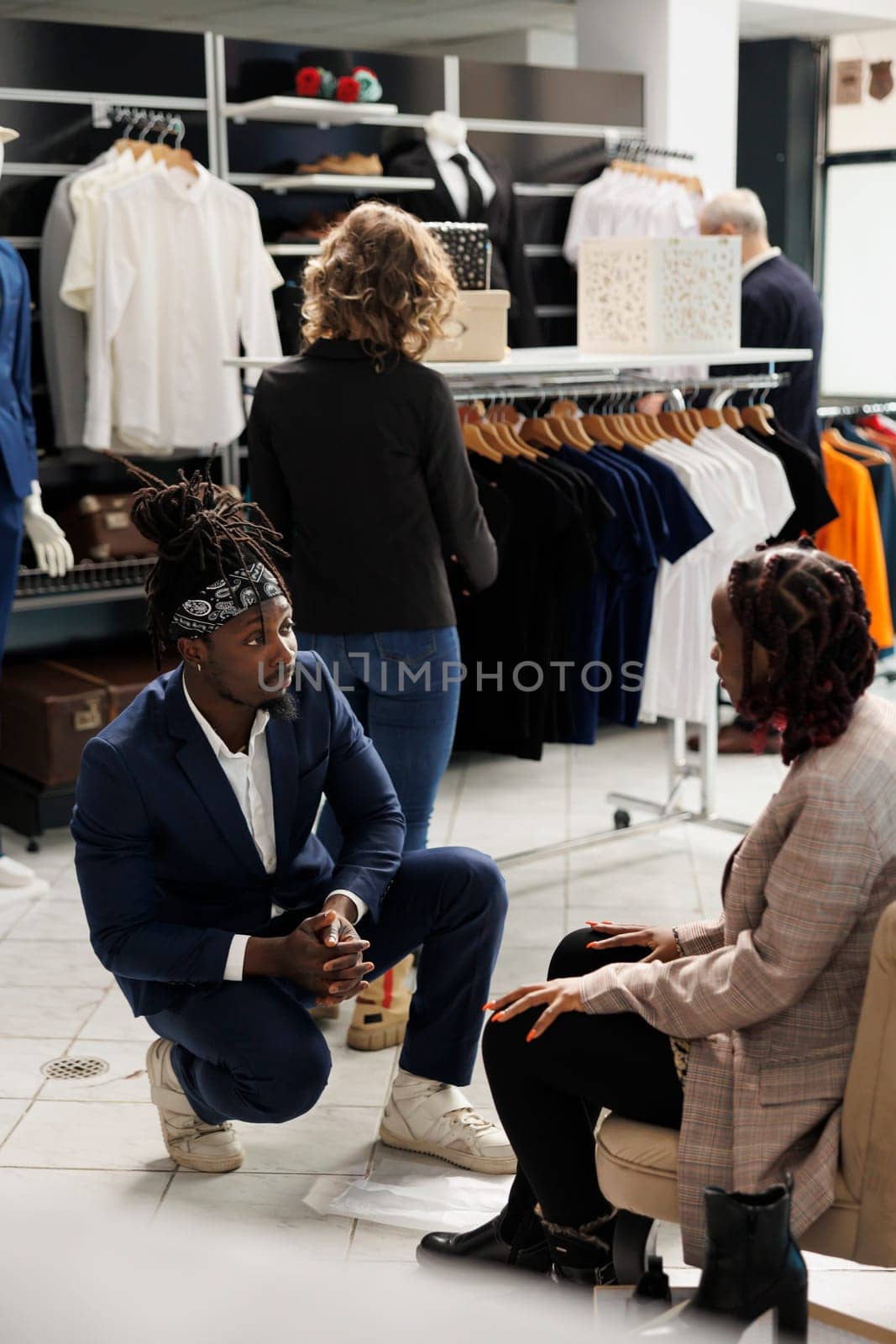 Showroom worker helping stylish client with right shoes for formal wear in shopping centre. African american woman customer buying fashionable clothes and merchandise in clothing store