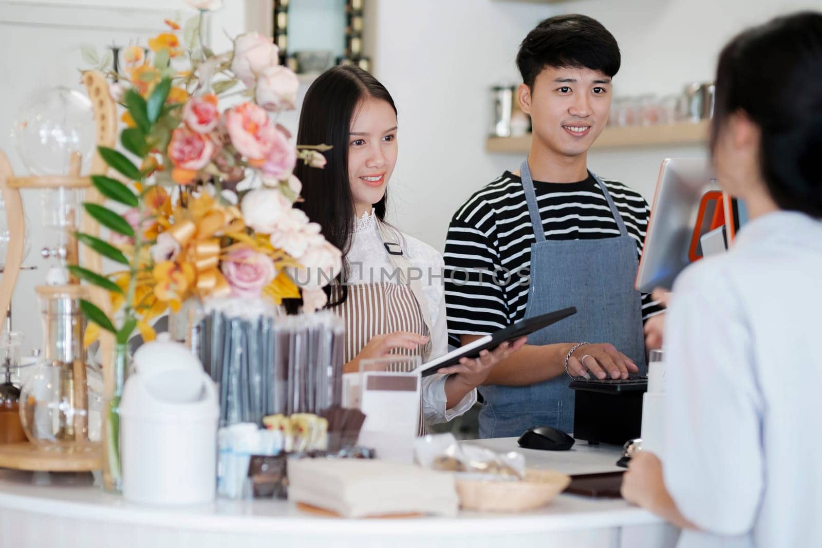 Asia Barista waiter take order from customer in coffee shop, cafe owner writing drink order at counter bar. Service mind concept. Point of Sale System, Take-out Foods, and Small Business Concepts.