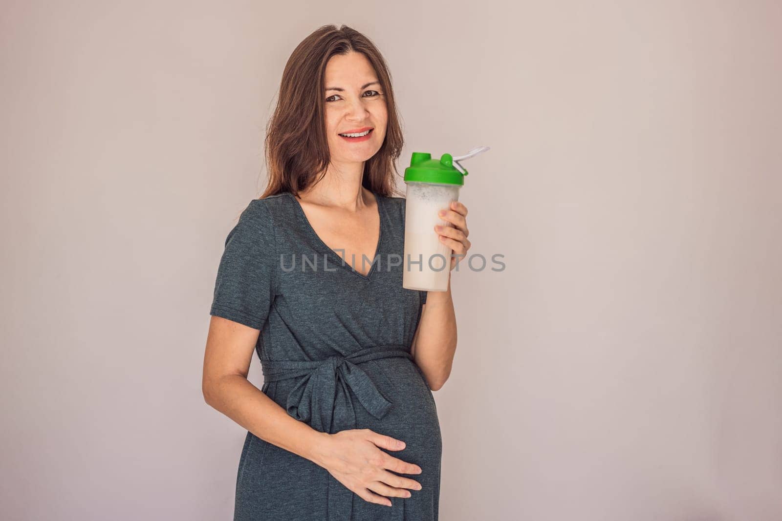 Energetic and fit pregnant woman after 40 enjoying a protein shake for a nourishing boost during her pregnancy journey. Embracing health and wellness for a thriving baby and mom.