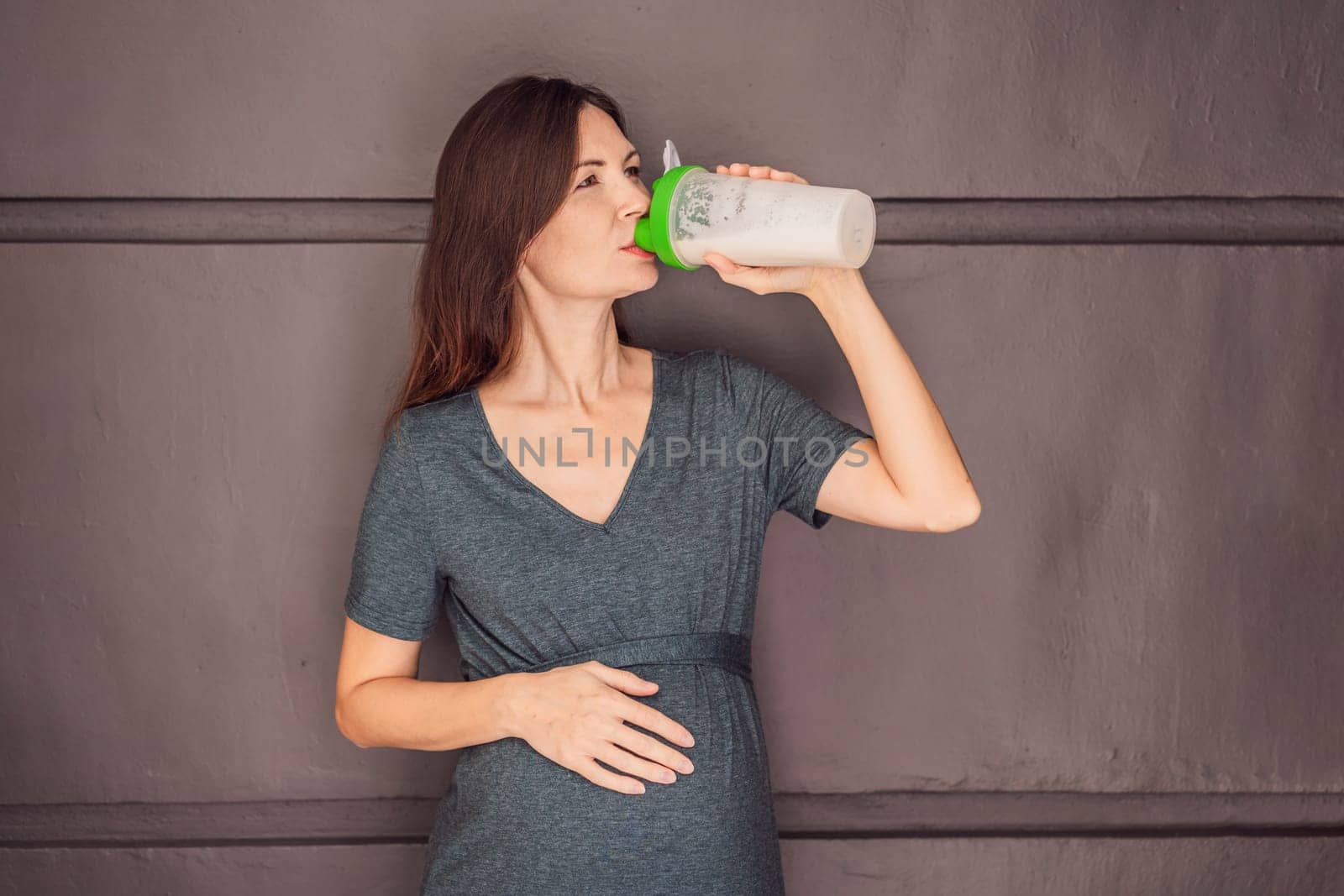 Energetic and fit pregnant woman after 40 enjoying a protein shake for a nourishing boost during her pregnancy journey. Embracing health and wellness for a thriving baby and mom.