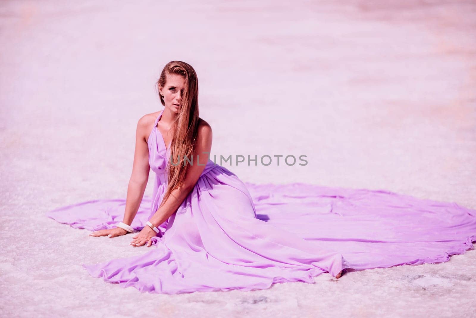 Pink lake woman. A woman in a pink dress sits on the salty shore of a pink lake and poses for a souvenir photo, creating lasting memories. by Matiunina