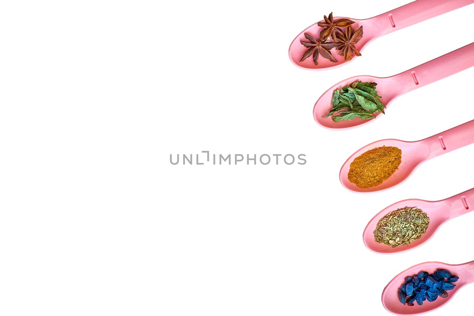 Pink spoons with spices for cooking on a green surface by jovani68