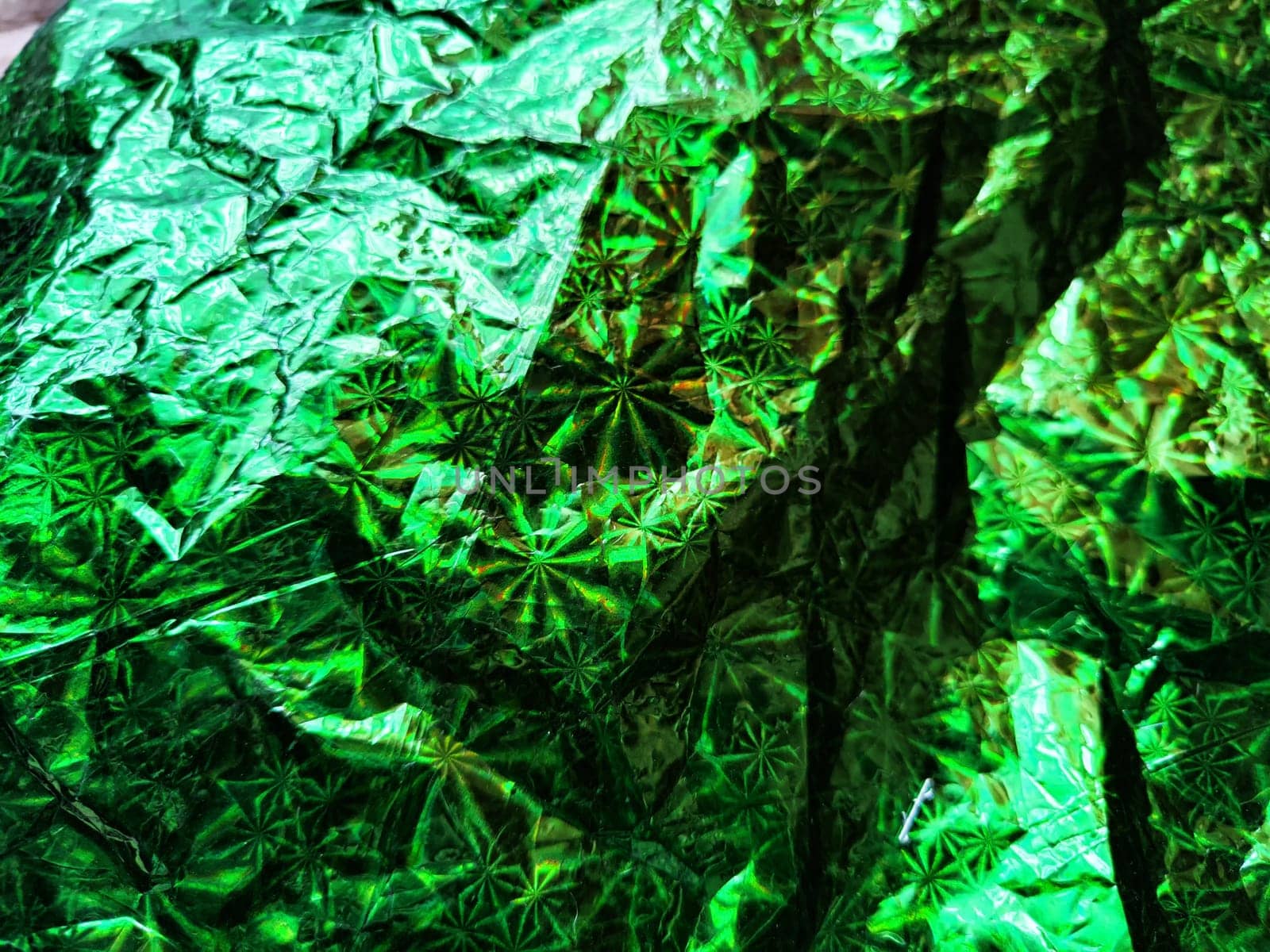 Beautiful abstract background and texture of crumpled aluminum foil in green color. Pattern, place for text and copy space