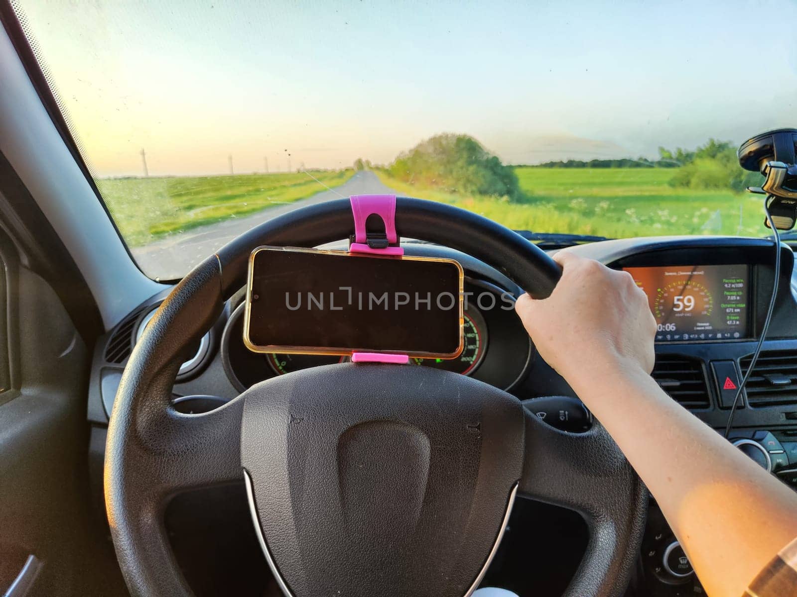Hand of woman on the steering wheel of car during a trip. The female driver travels alone. Trip in summer time