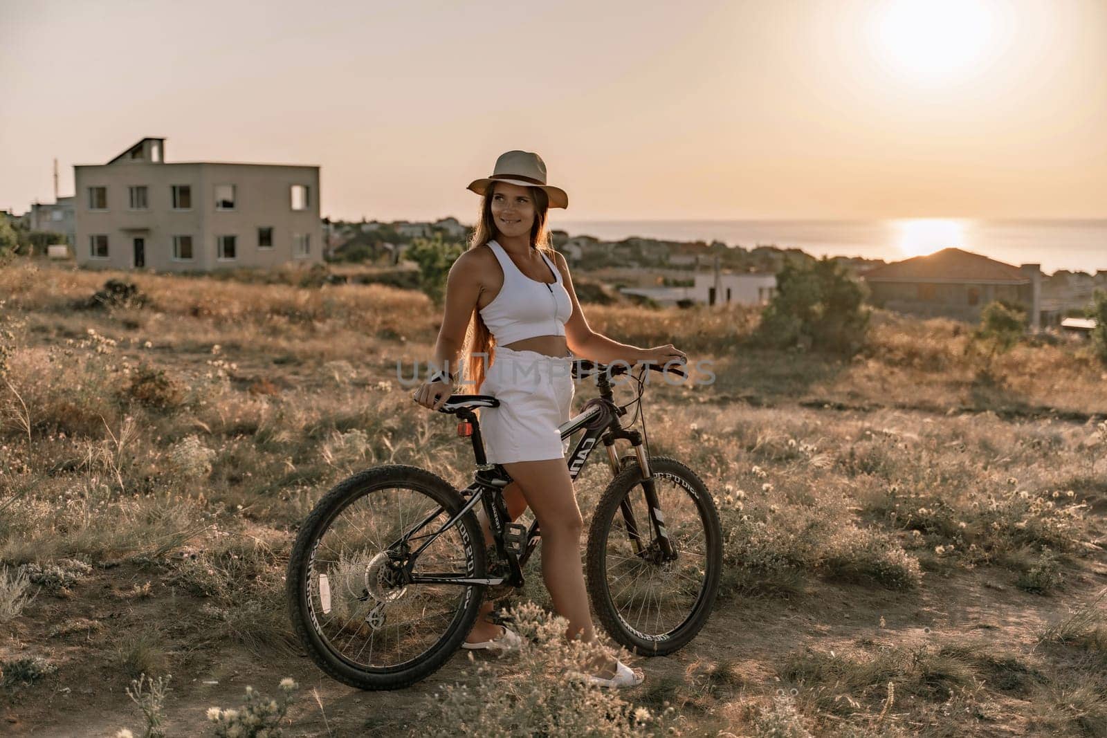 A woman cyclist on a mountain bike looking at the landscape sea. Adventure travel on bike