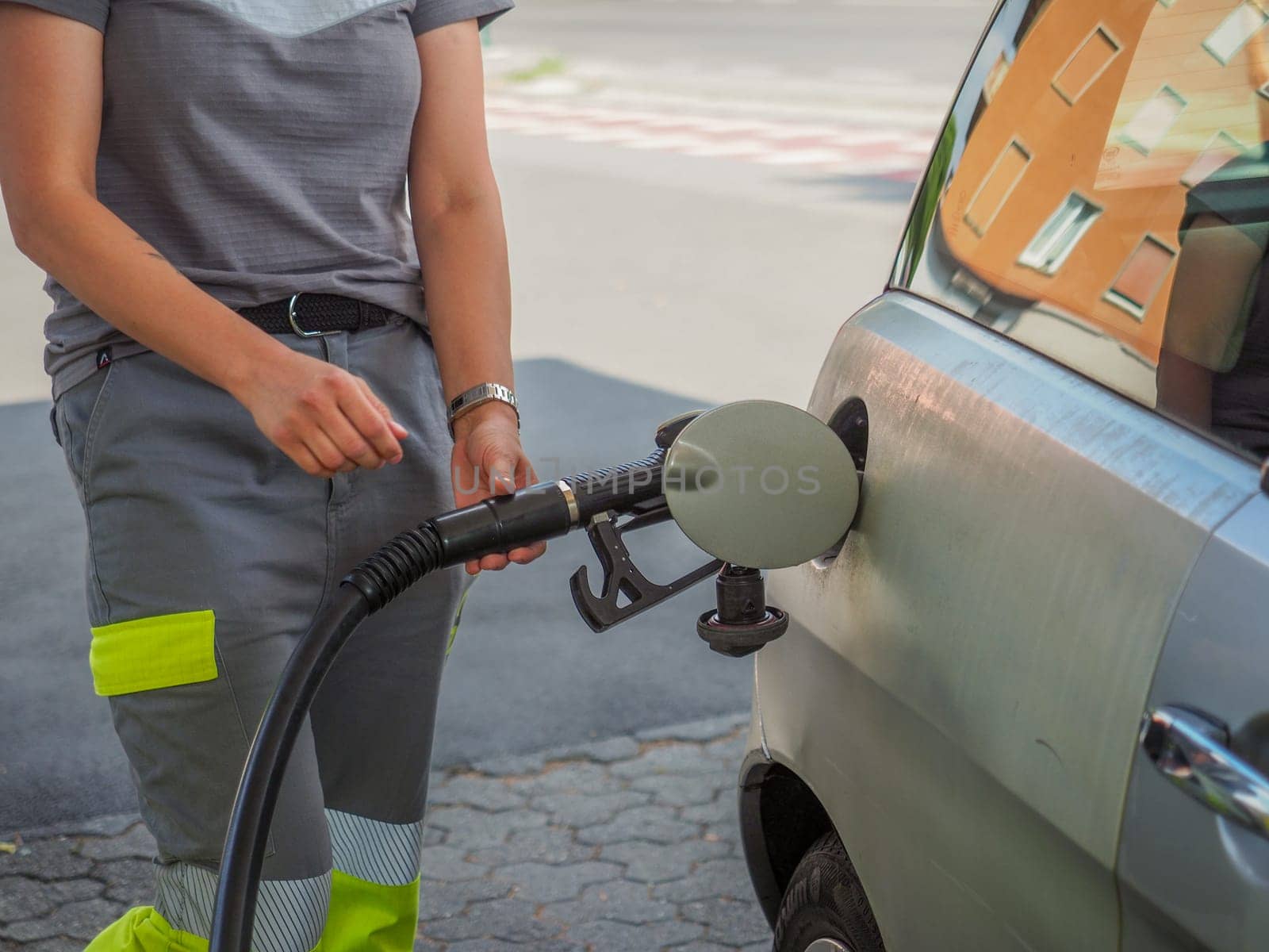 Cremona, Italy - July 3 2023 caucasian service woman at Eni Agip city fuel station pumping petrol to a customer car