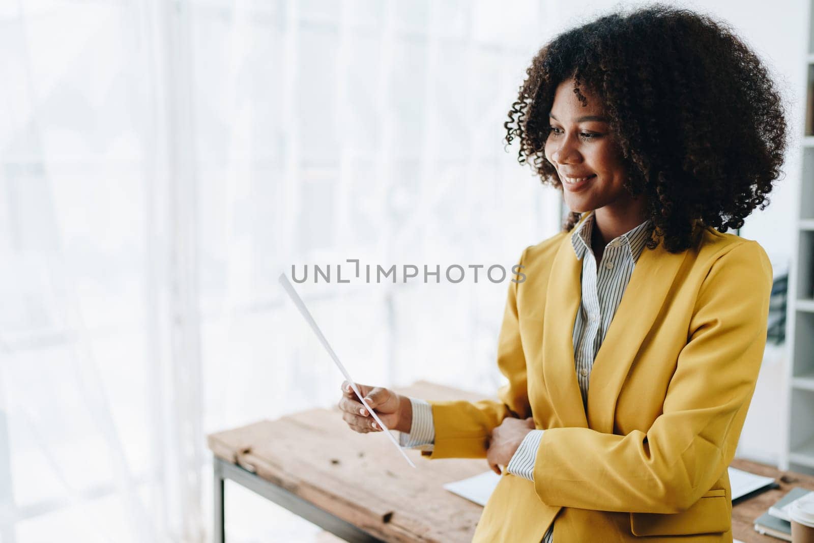 Beautiful young African american businesswoman using laptop computer and paperworks with planning working on financial document, tax, exchange, accounting and Financial advisor by Manastrong