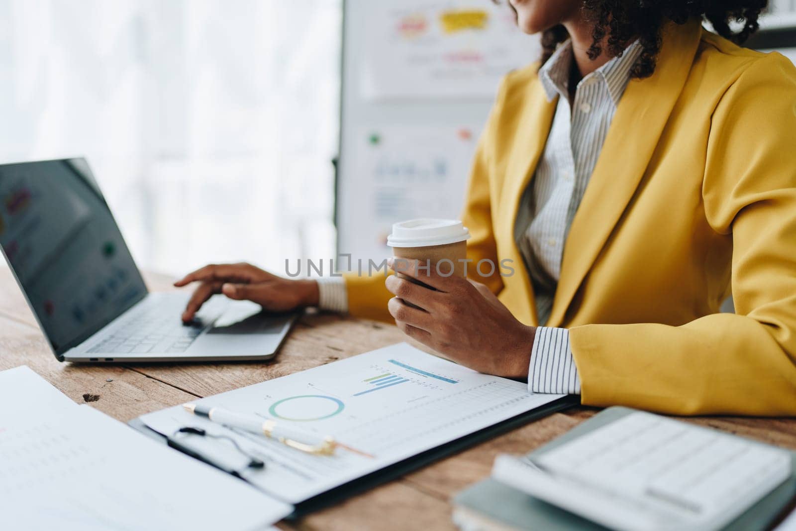 Beautiful young African american businesswoman using laptop computer and paperworks with planning working on financial document, tax, exchange, accounting and Financial advisor by Manastrong