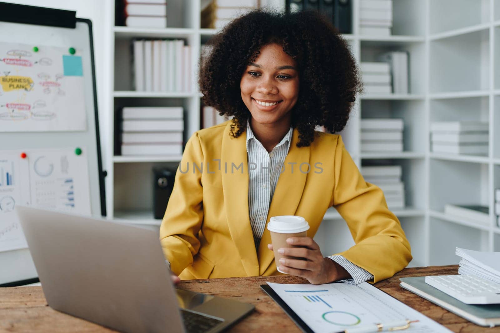 Beautiful young African american businesswoman using laptop computer and paperworks with planning working on financial document, tax, exchange, accounting and Financial advisor by Manastrong