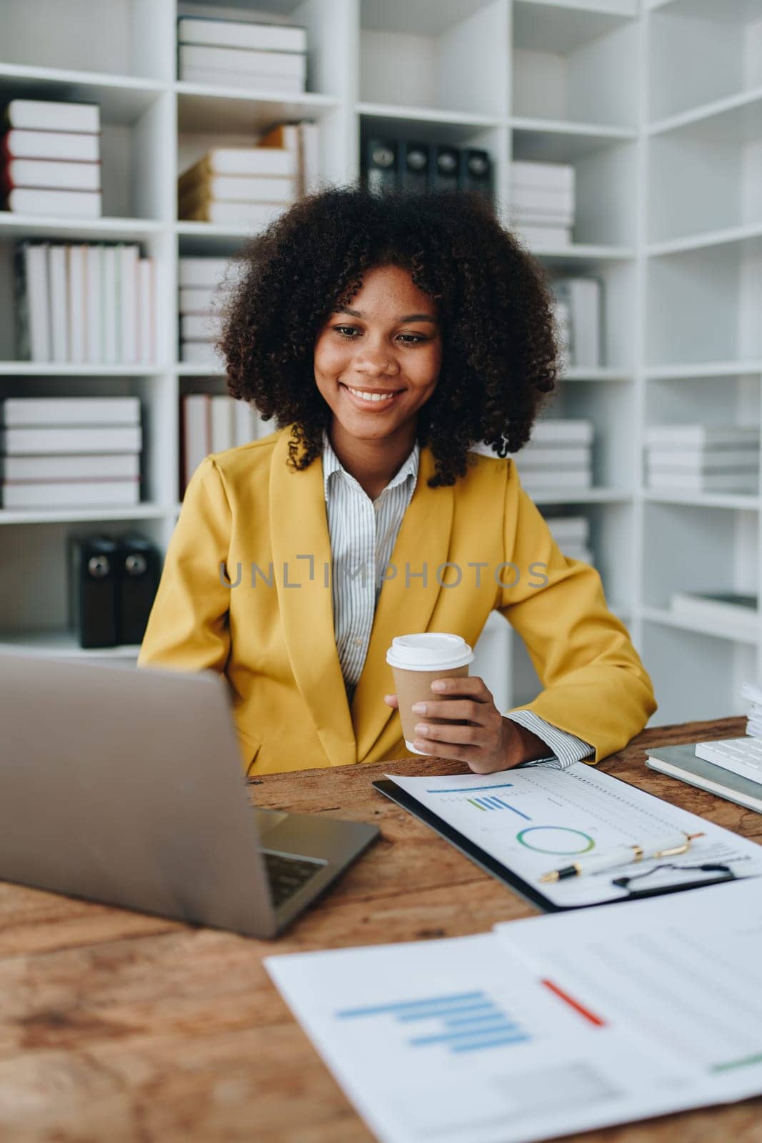 Beautiful young African american businesswoman using laptop computer and paperworks with planning working on financial document, tax, exchange, accounting and Financial advisor.