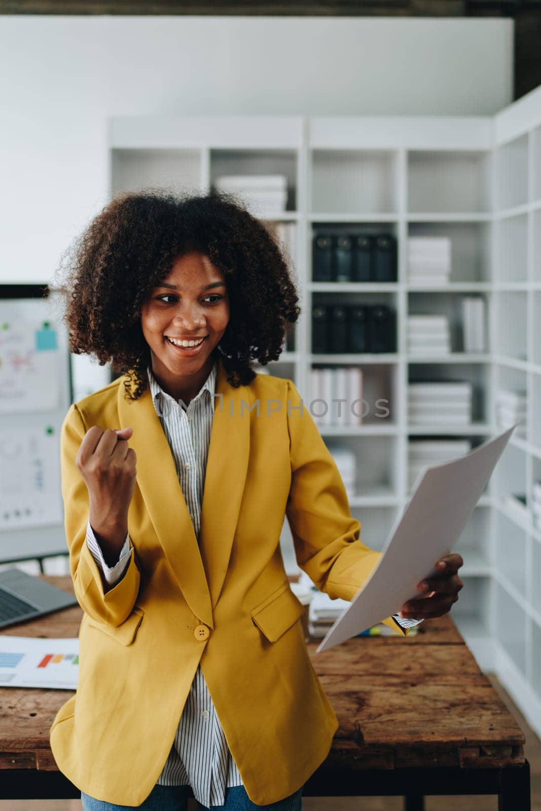 American African business woman using document, computer laptop, calculator, paperwork, documents, in winner and smiling Happy to be successful achievement success. finance and investment concepts by Manastrong