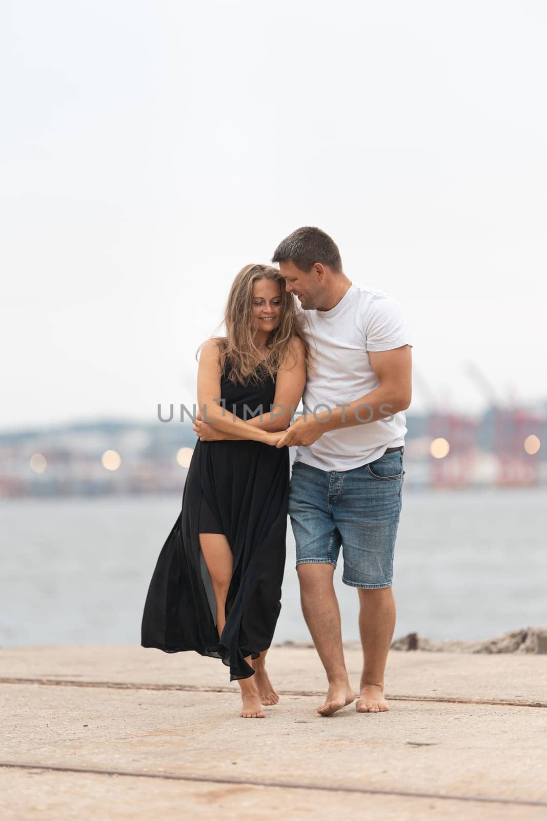 Cute romantic married couple dancing on the pier. Vertical shot