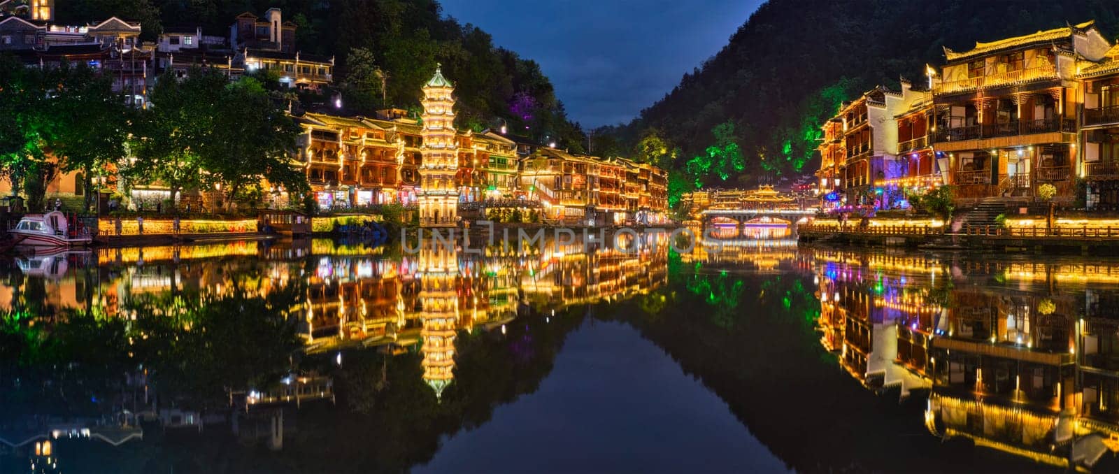 Chinese tourist attraction destination - Feng Huang Ancient Town (Phoenix Ancient Town) on Tuo Jiang River illuminated at night. Hunan Province, China