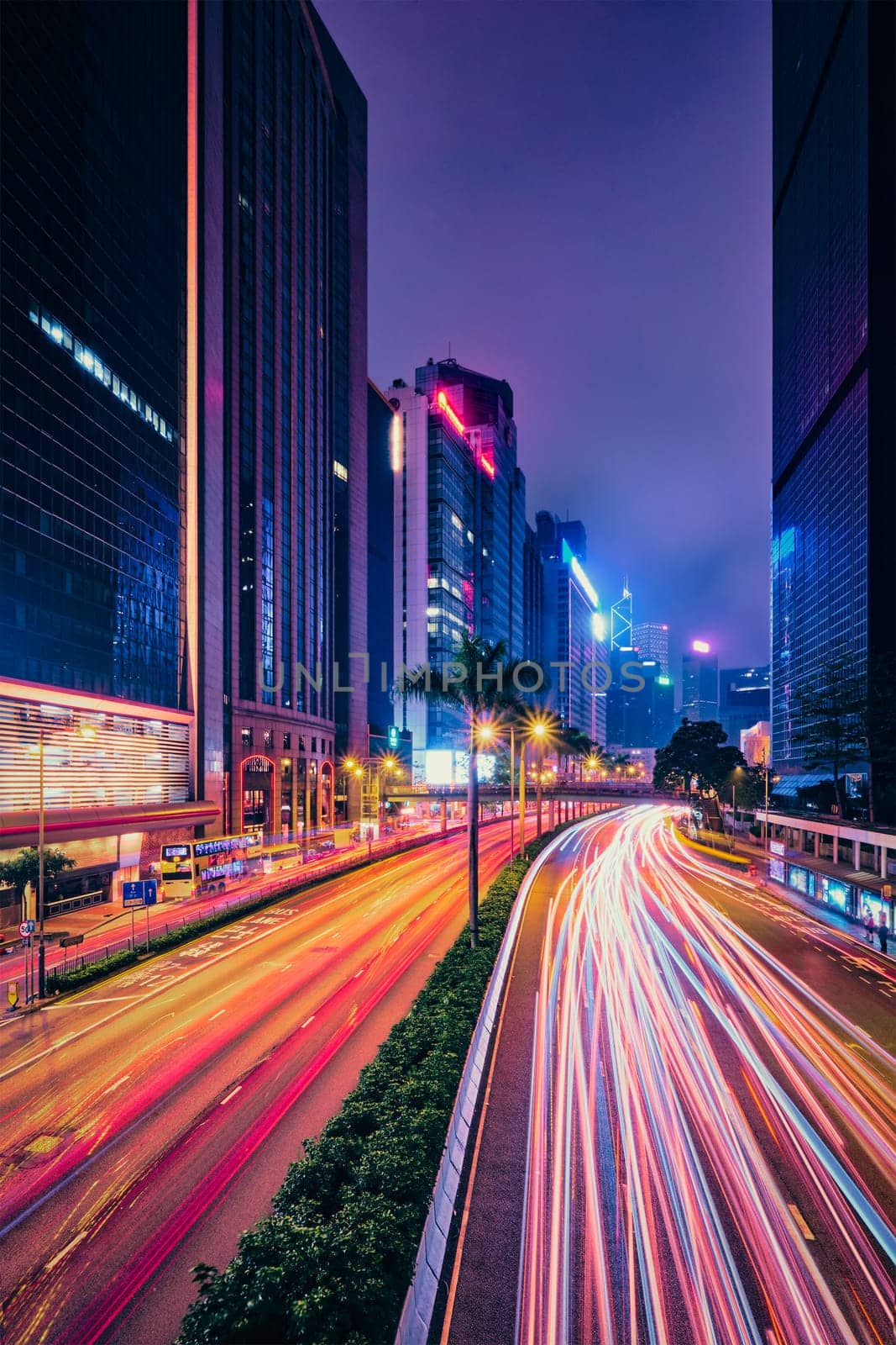 Street traffic in Hong Kong at night. Office skyscraper buildings and busy traffic on highway road with blurred cars light trails. Hong Kong, China