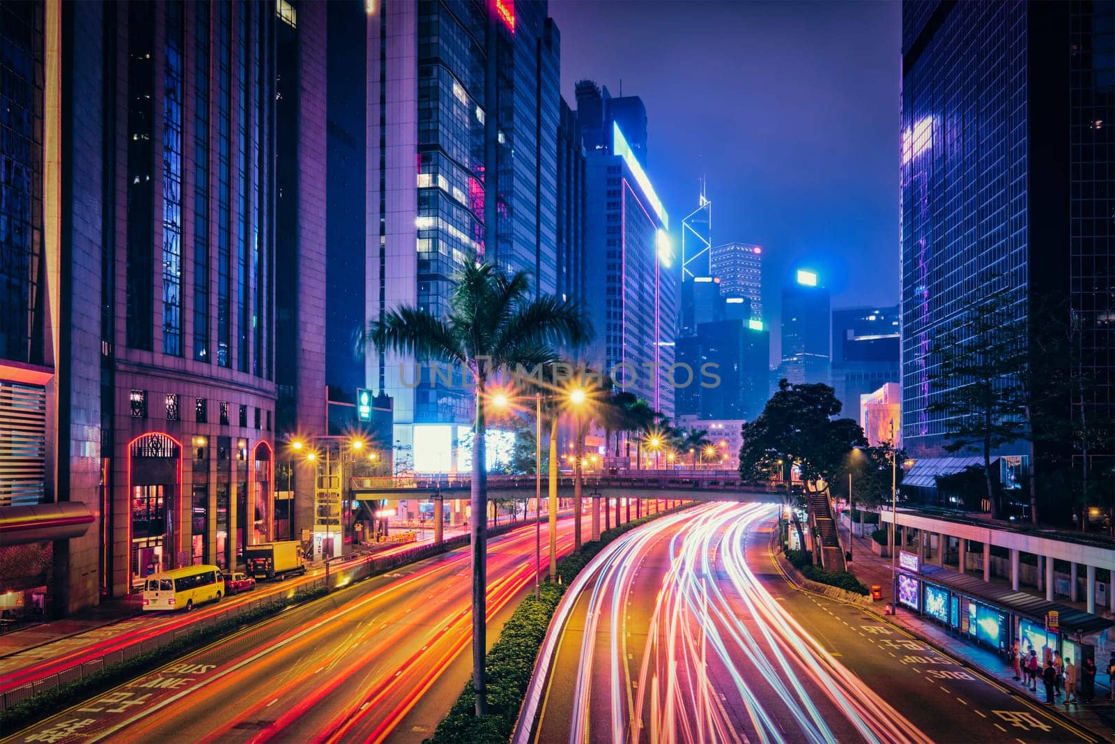 Street traffic in Hong Kong at night. Office skyscraper buildings and busy traffic on highway road with blurred cars light trails. Hong Kong, China