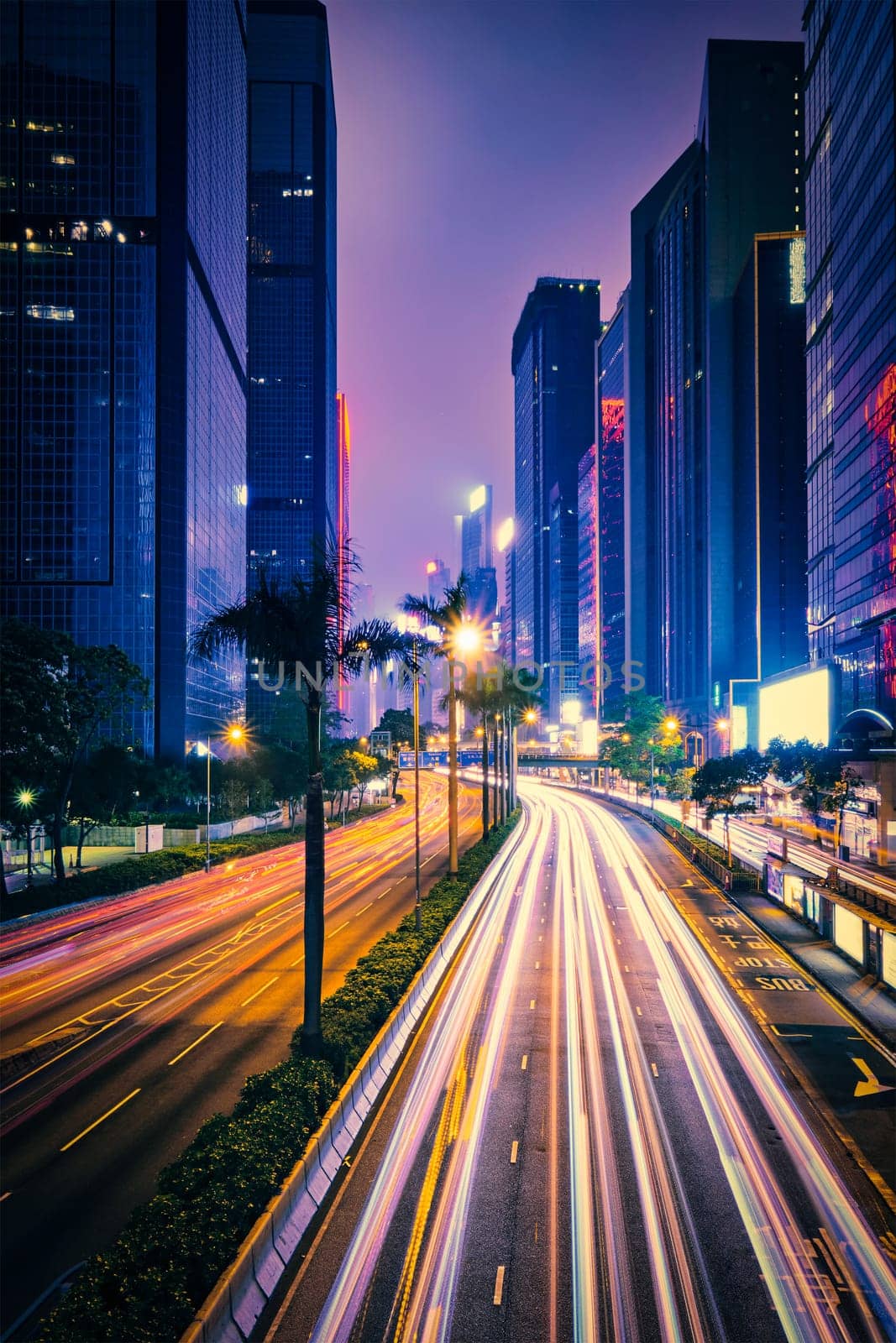 Street traffic in Hong Kong at night. Office skyscraper buildings and busy traffic on highway road with blurred cars light trails. Hong Kong, China