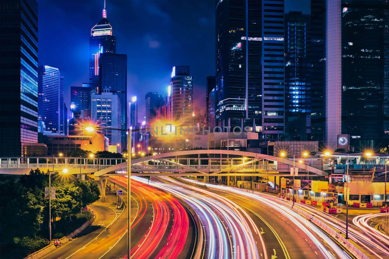 Street traffic in Hong Kong at night. Office skyscraper buildings and busy traffic on highway road with blurred cars light trails. Hong Kong, China