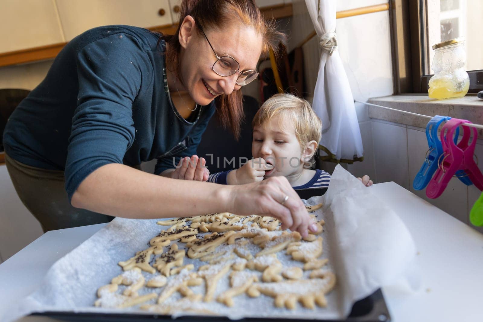 Smiling woman with her little son make cookies on the kitchen by Studia72