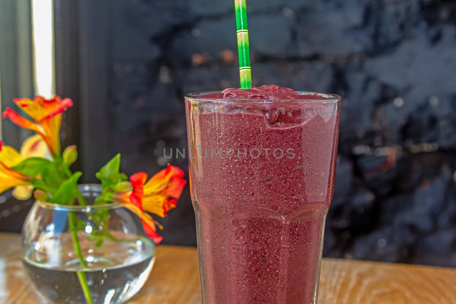 black currant smoothie in glassful on dark background.