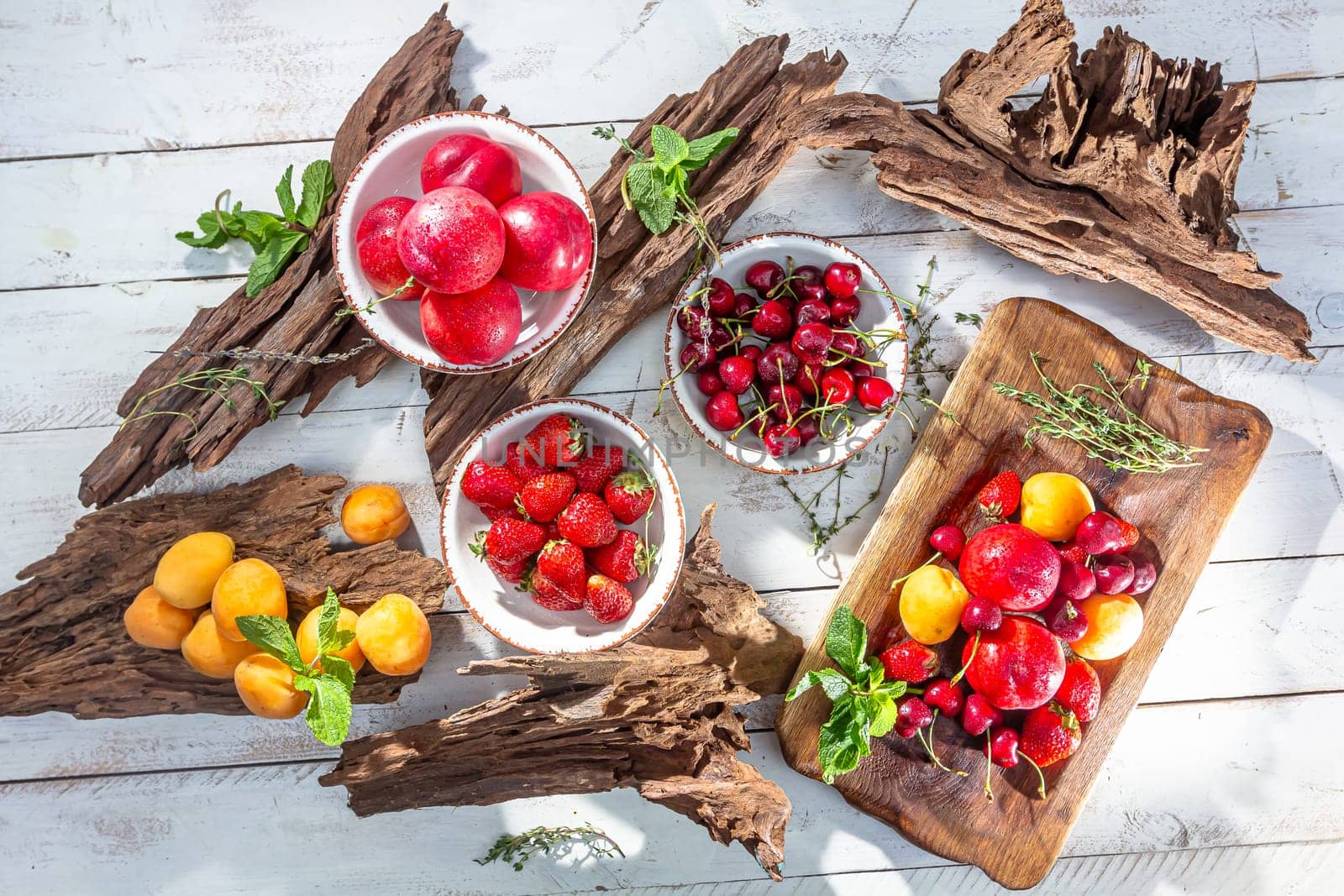 Fresh berries and fruits on a old-fashioned wooden plate on rotten stump. Countryside. by Milanchikov