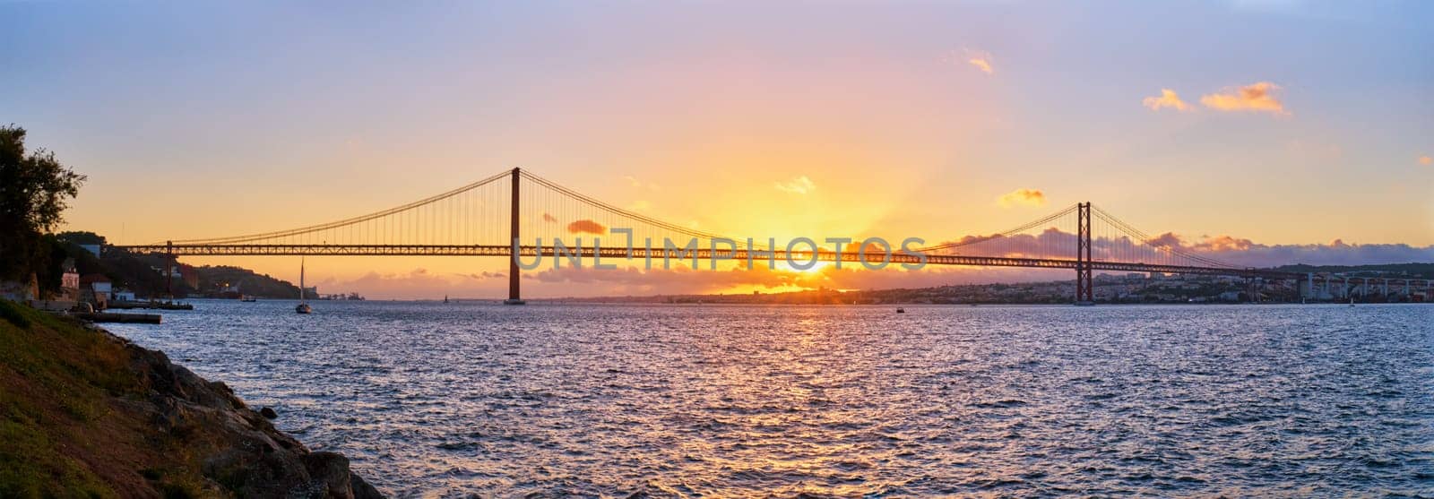 Panorama of 25 de Abril Bridge over Tagus river on sunset. Lisbon, Portugal by dimol