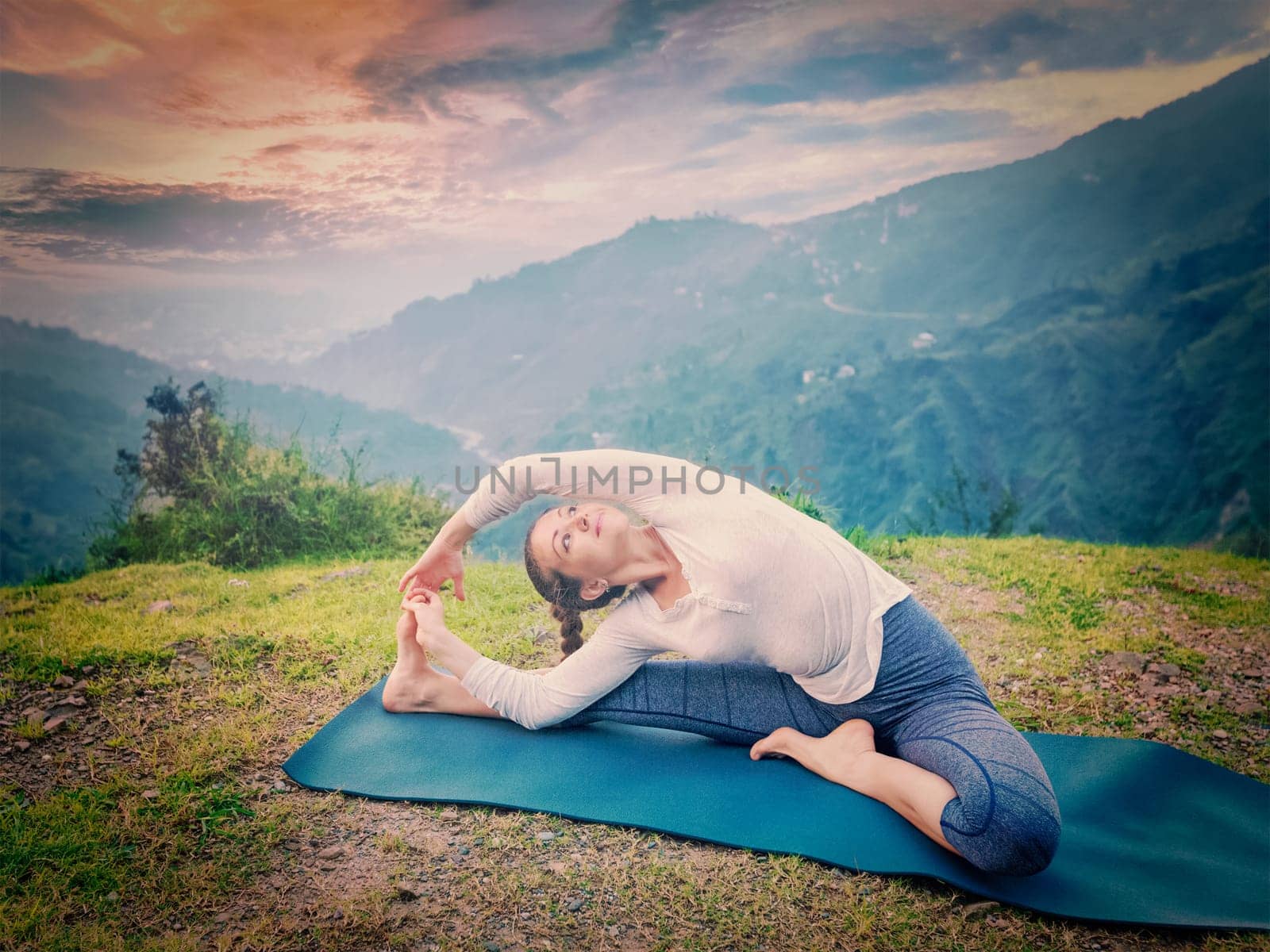 Yoga outdoors - young sporty fit woman doing Hatha Yoga asana janu sirsasana - Revolved Head-to-Knee Pose - in. Vintage retro effect filtered hipster style image.