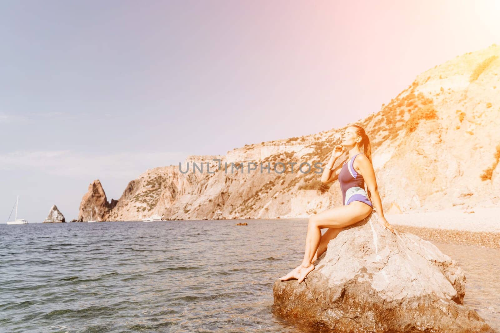 Woman travel summer sea. A happy tourist in a blue bikini enjoying the scenic view of the sea and volcanic mountains while taking pictures to capture the memories of her travel adventure. by Matiunina