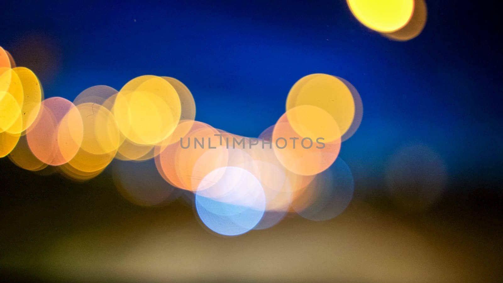 Blurred lights evening city traffic bokeh. Defocused night city traffic. Blurred lights bokeh car headlights driving evening city road. City night traffic background by Matiunina